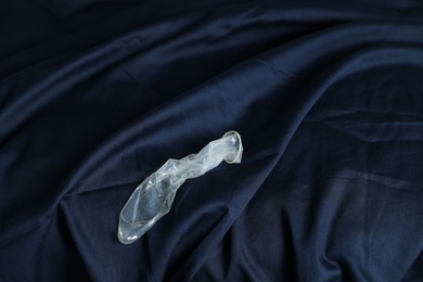 Photo of Unrolled condom on bed, above view. Safe sex