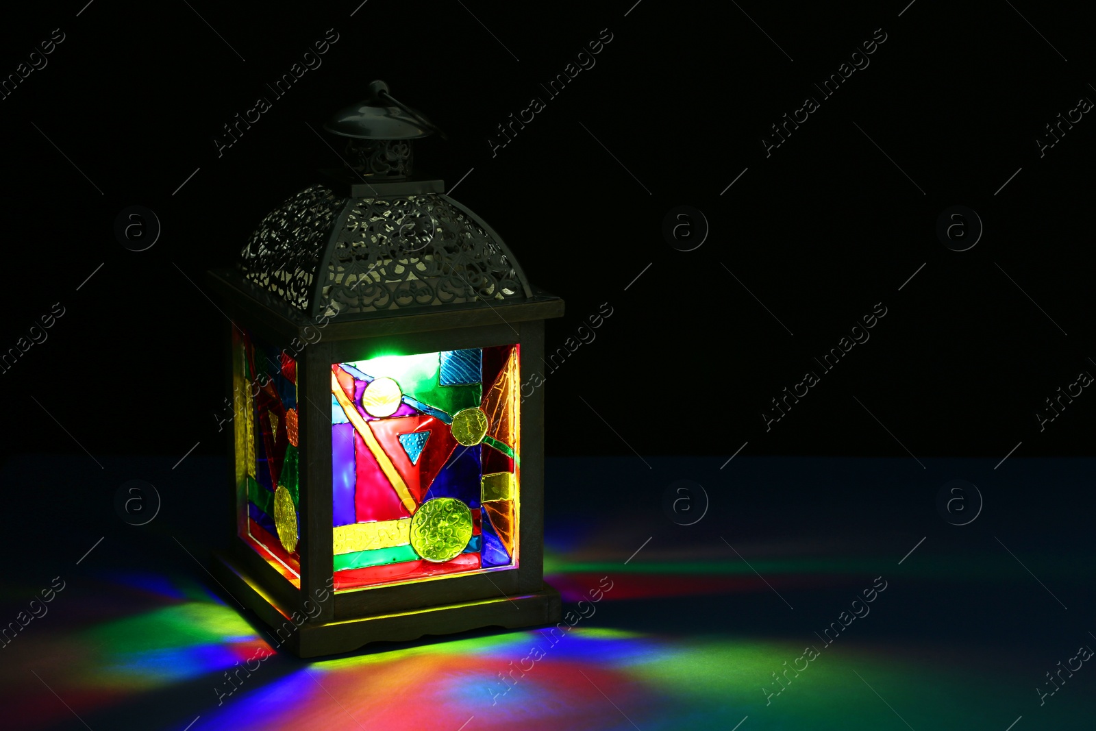 Photo of Decorative Arabic lantern on table against dark background. Space for text