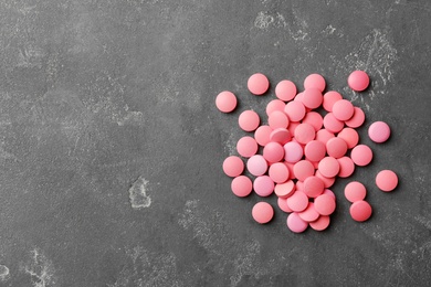 Photo of Heap of pills on grey background, top view. Space for text