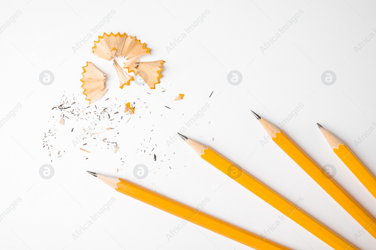 Photo of Graphite pencils and shavings on white background, top view