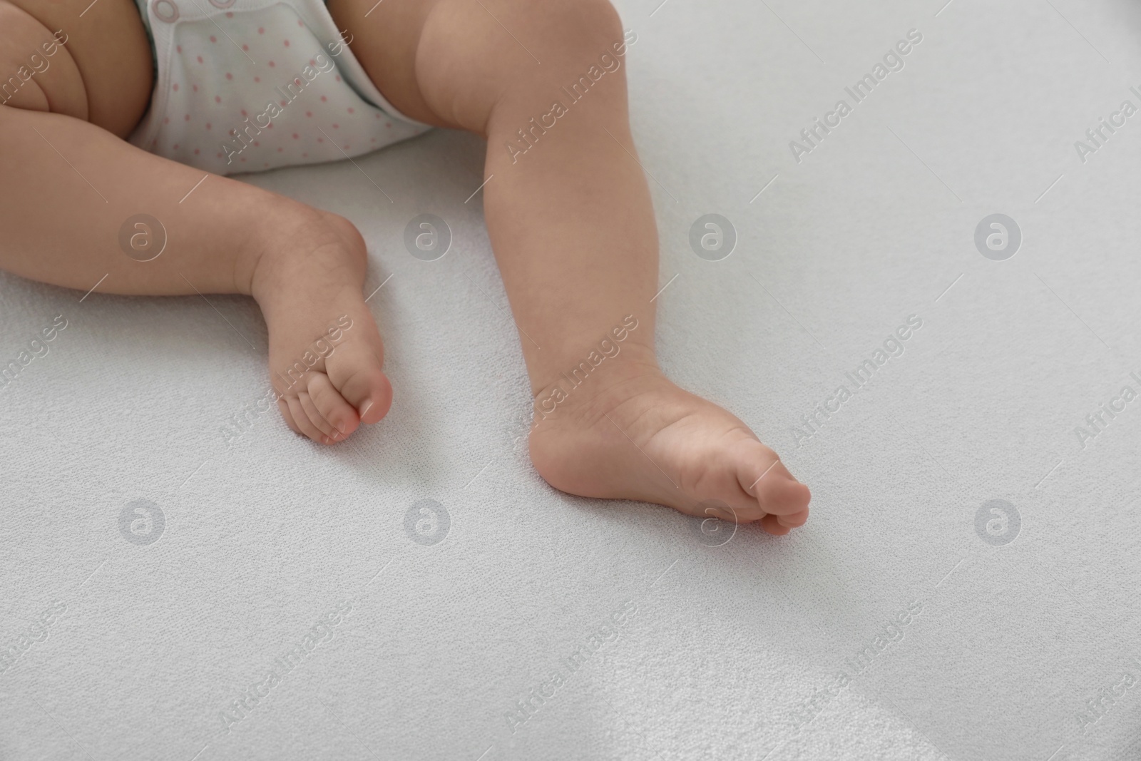 Photo of Little baby lying on bed, closeup. Space for text