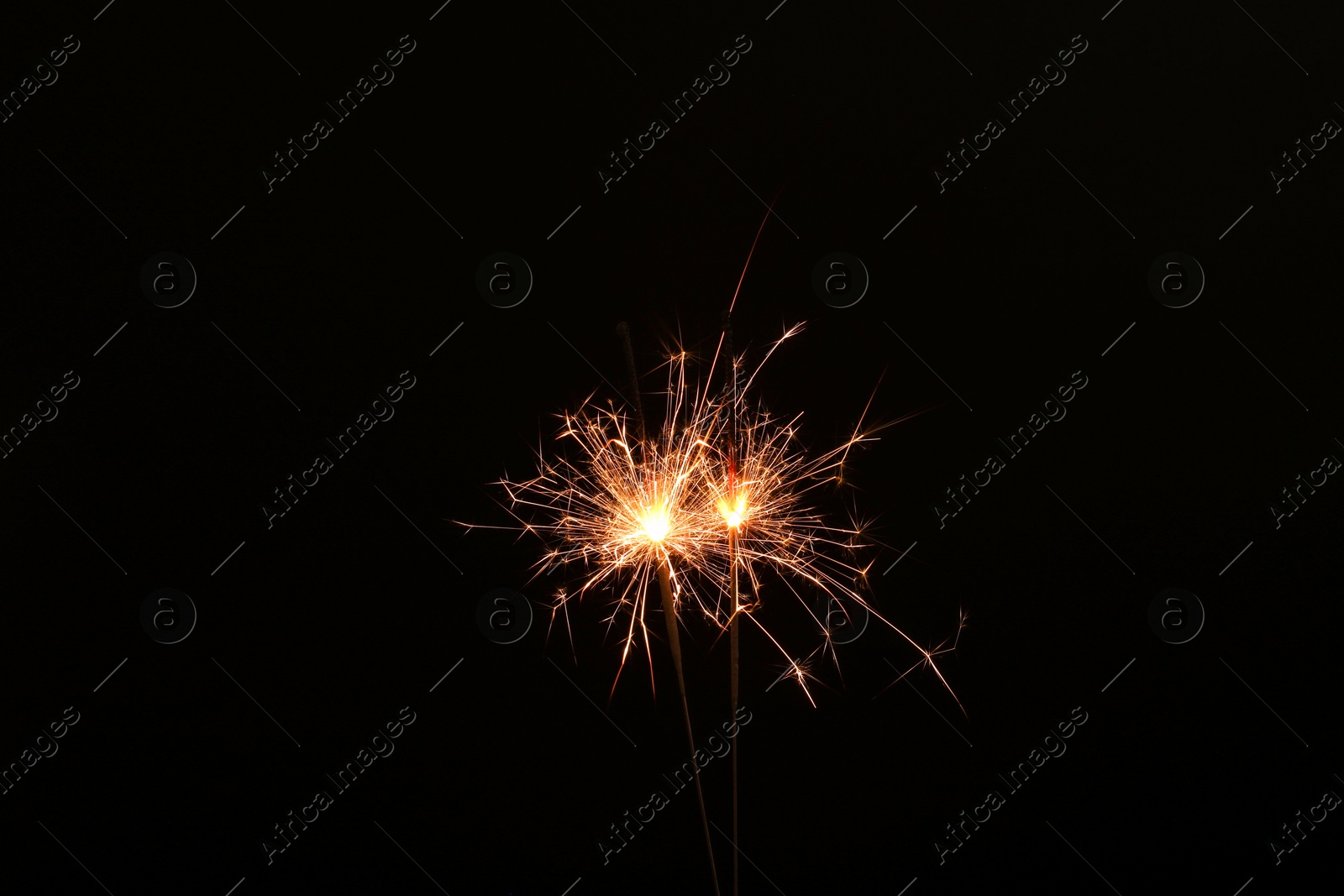Photo of Burning sparklers glowing in dark, space for text