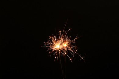 Photo of Burning sparklers glowing in dark, space for text