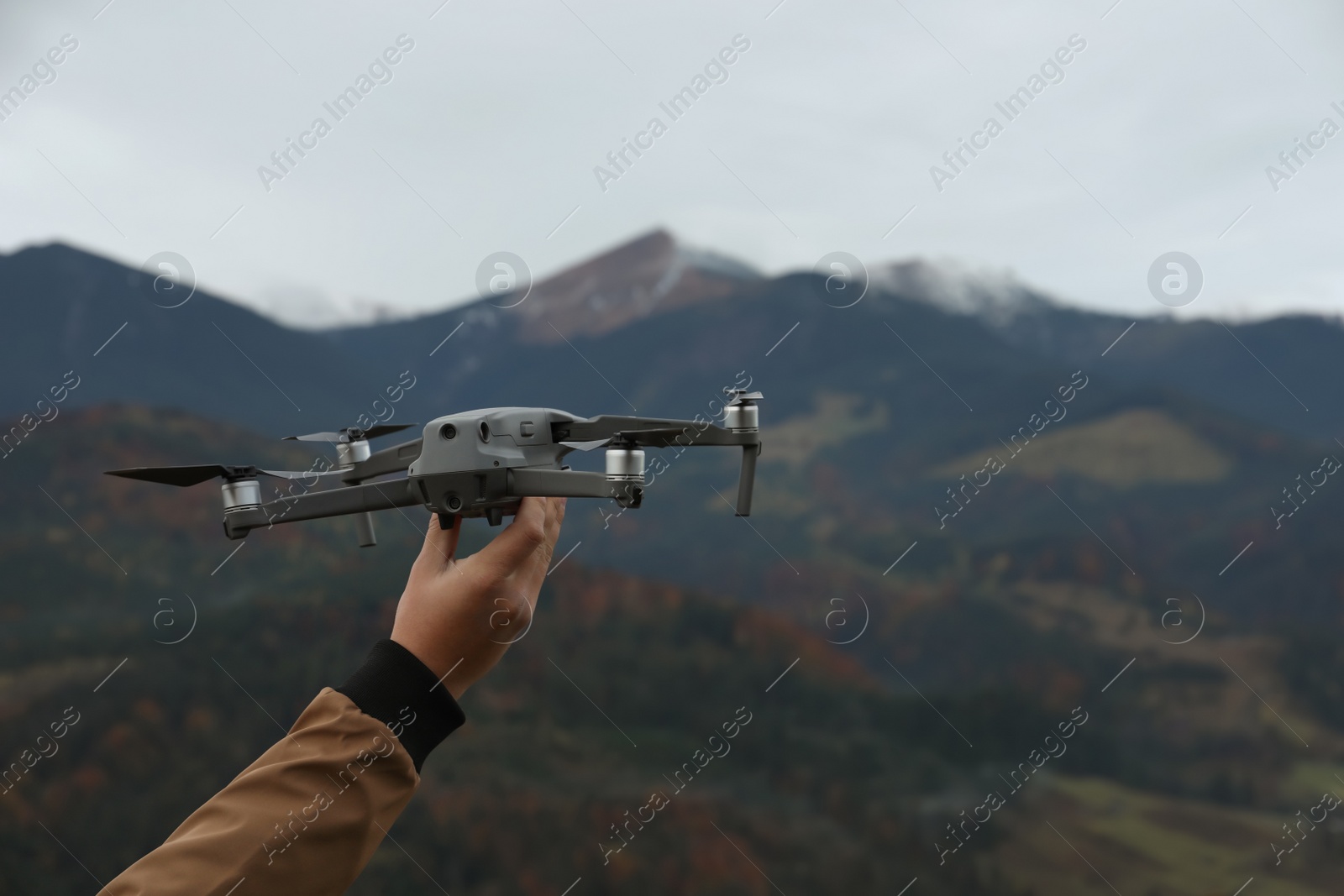 Photo of Man with modern drone in mountains, closeup. Space for text