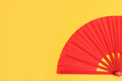 Photo of Red hand fan on yellow background, top view. Space for text