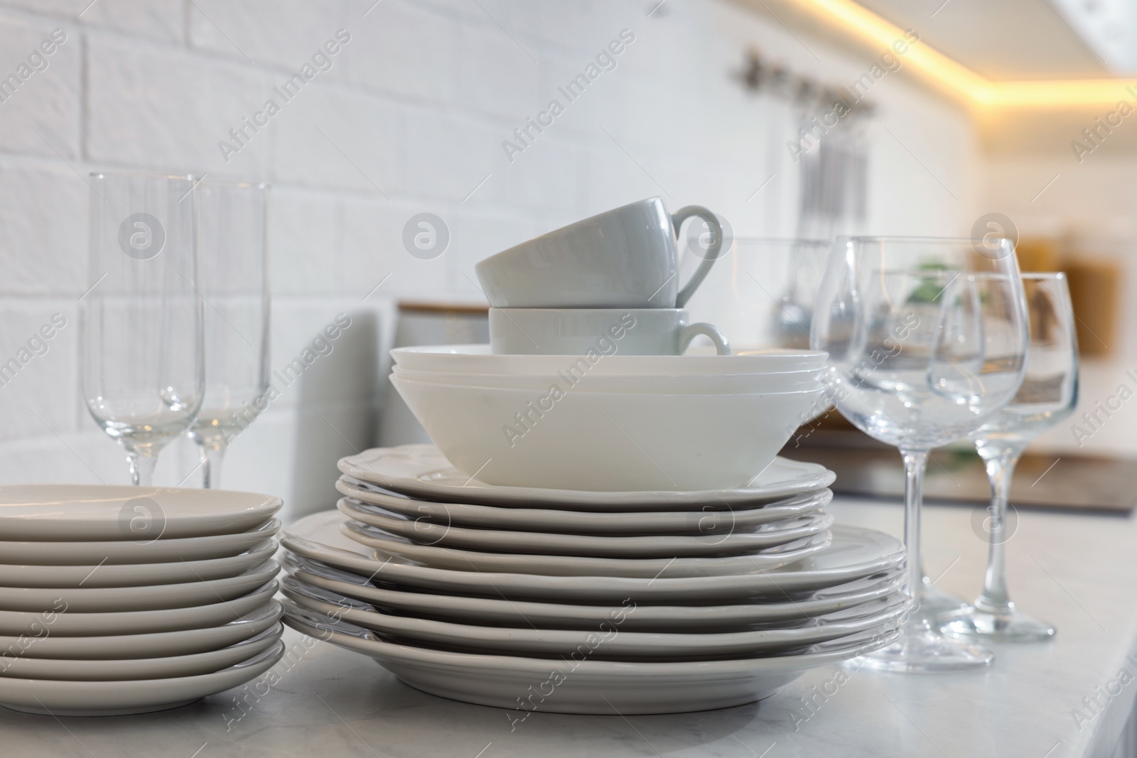 Photo of Different clean dishware, cups and glasses on countertop in kitchen