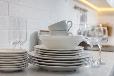 Photo of Different clean dishware, cups and glasses on countertop in kitchen