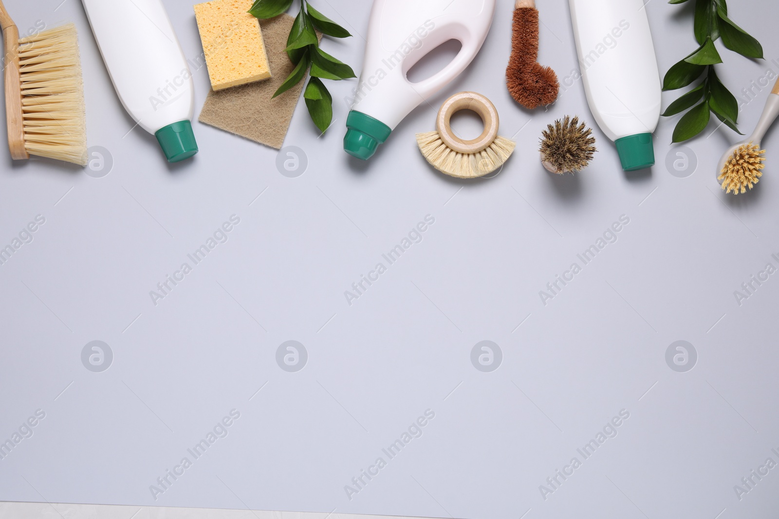 Photo of Flat lay composition with different cleaning supplies on light gray background, space for text