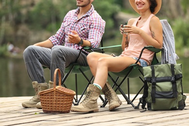 Photo of Young couple resting on pier near lake. Camping season