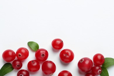 Photo of Fresh ripe cranberries and green leaves on white background, flat lay. Space for text
