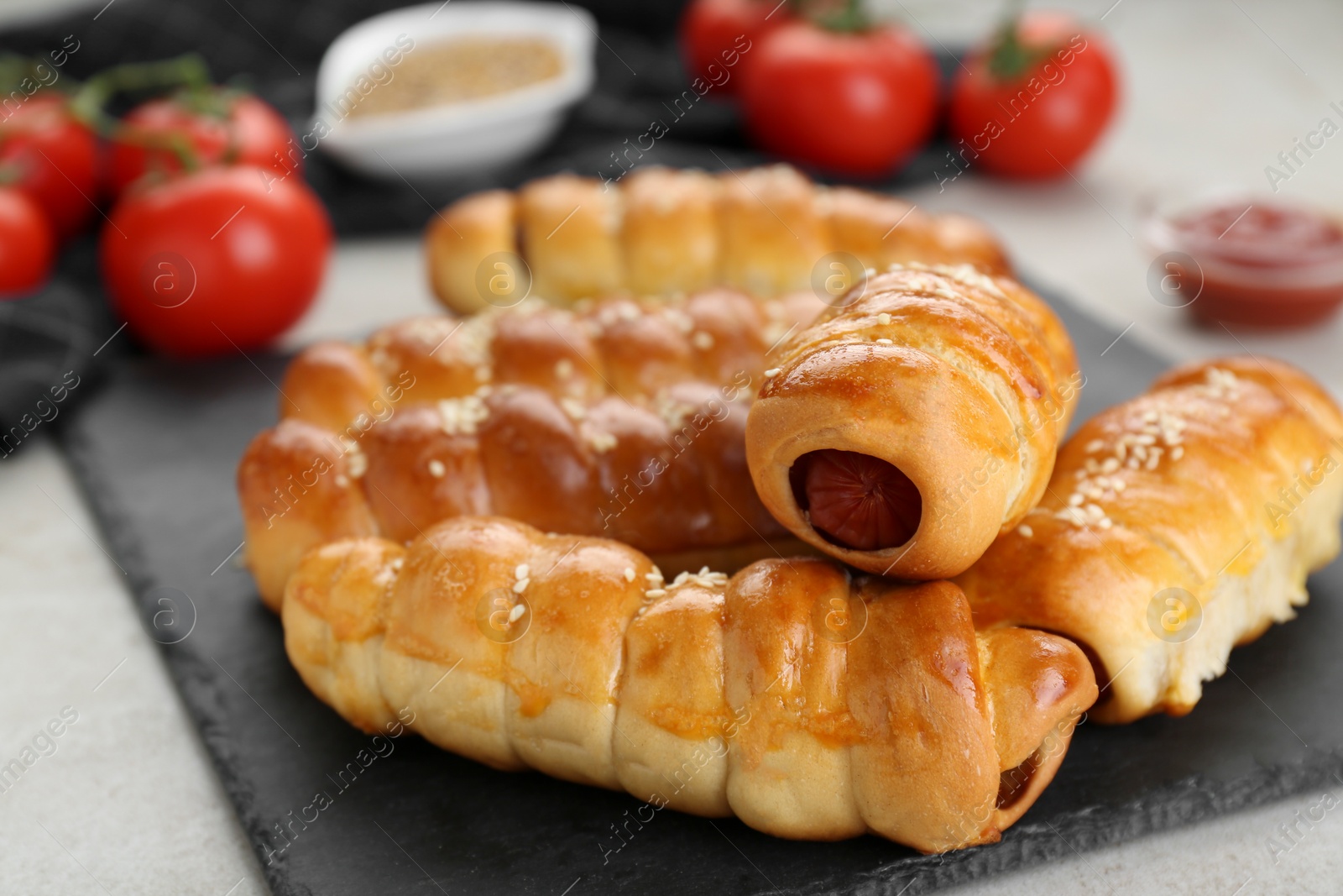 Photo of Delicious sausage rolls and ingredients on beige table, closeup