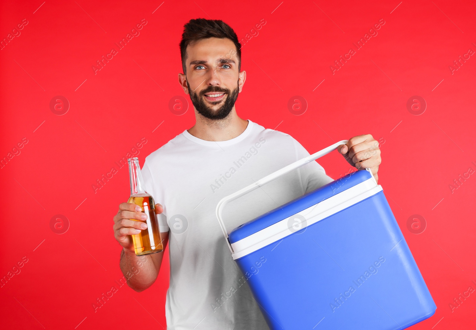 Photo of Happy man with cool box and bottle of beer on red background