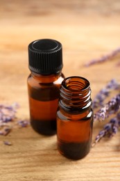 Photo of Essential oil and lavender flowers on wooden table, closeup