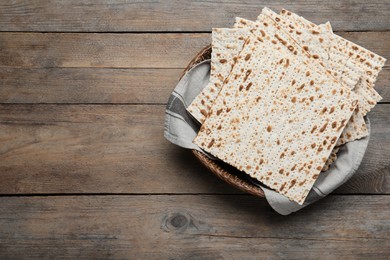 Photo of Traditional matzos in basket on wooden table, top view. Space for text
