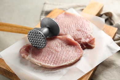 Photo of Cooking schnitzel. Raw pork chops and meat mallet on grey table, closeup