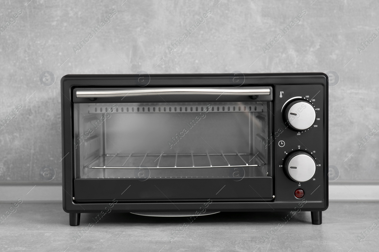 Photo of One electric oven on light grey table. Cooking appliance