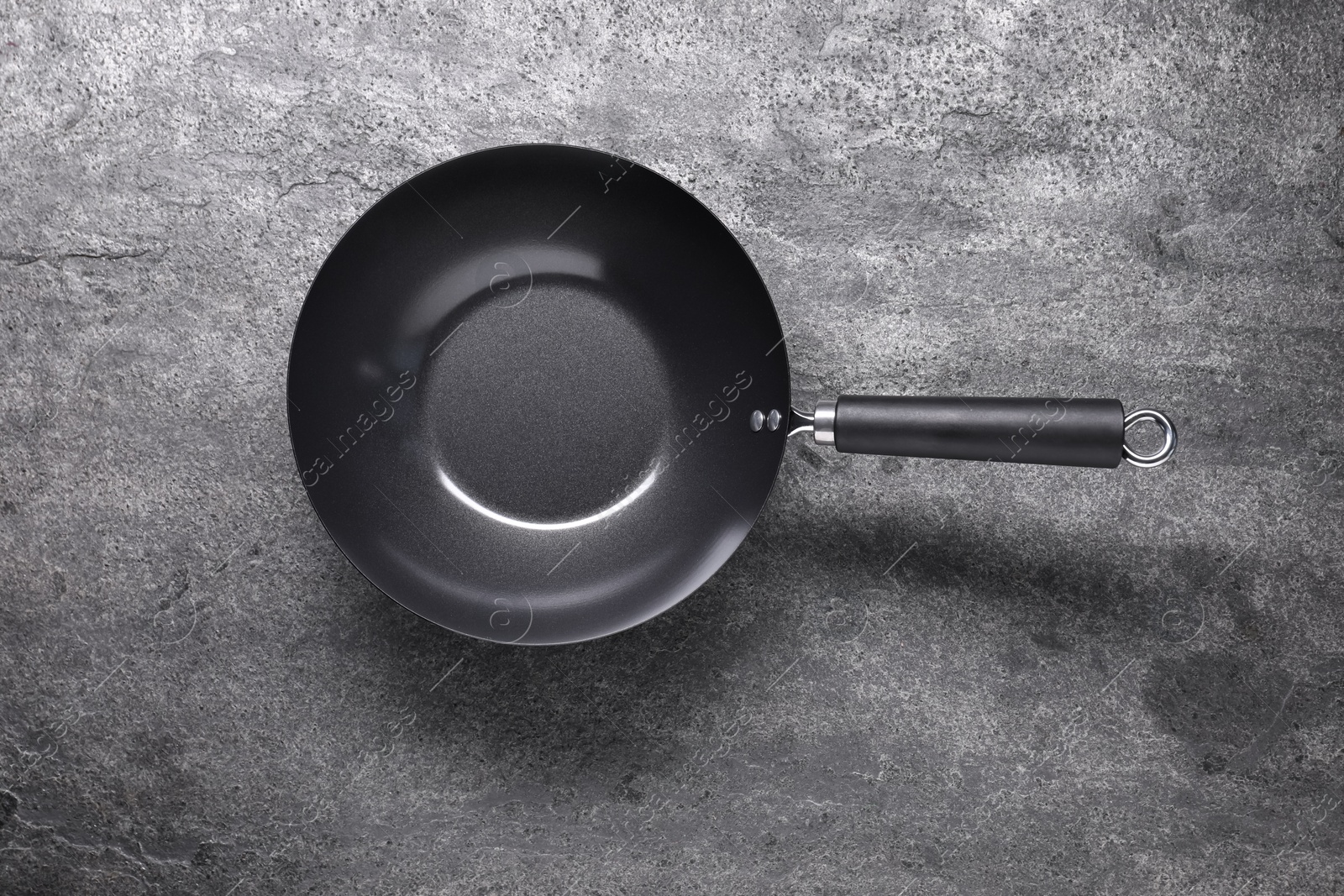 Photo of Empty iron wok on grey textured table, top view. Chinese cookware