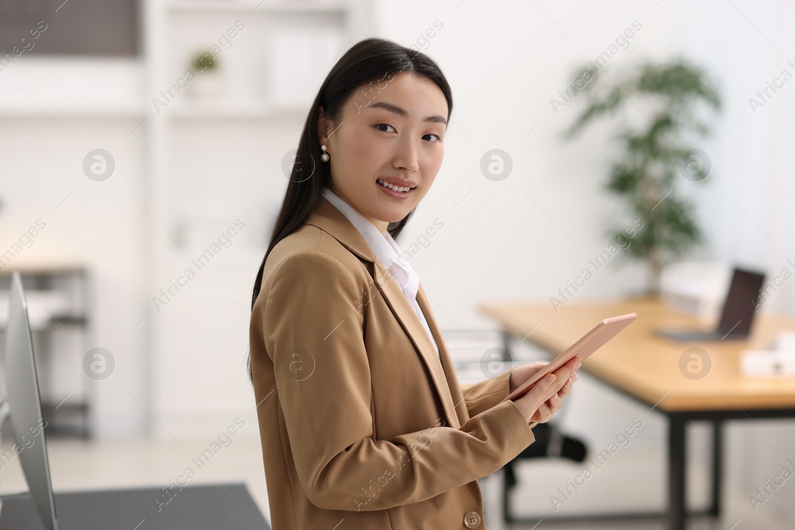 Photo of Portrait of smiling businesswoman with tablet in office