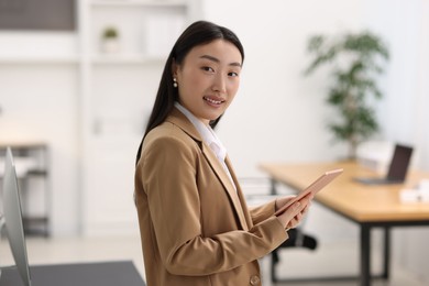 Photo of Portrait of smiling businesswoman with tablet in office
