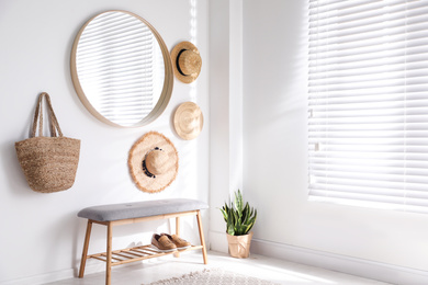 Stylish round mirror hanging on white wall in room