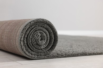Photo of Rolled grey carpet on floor in room, closeup