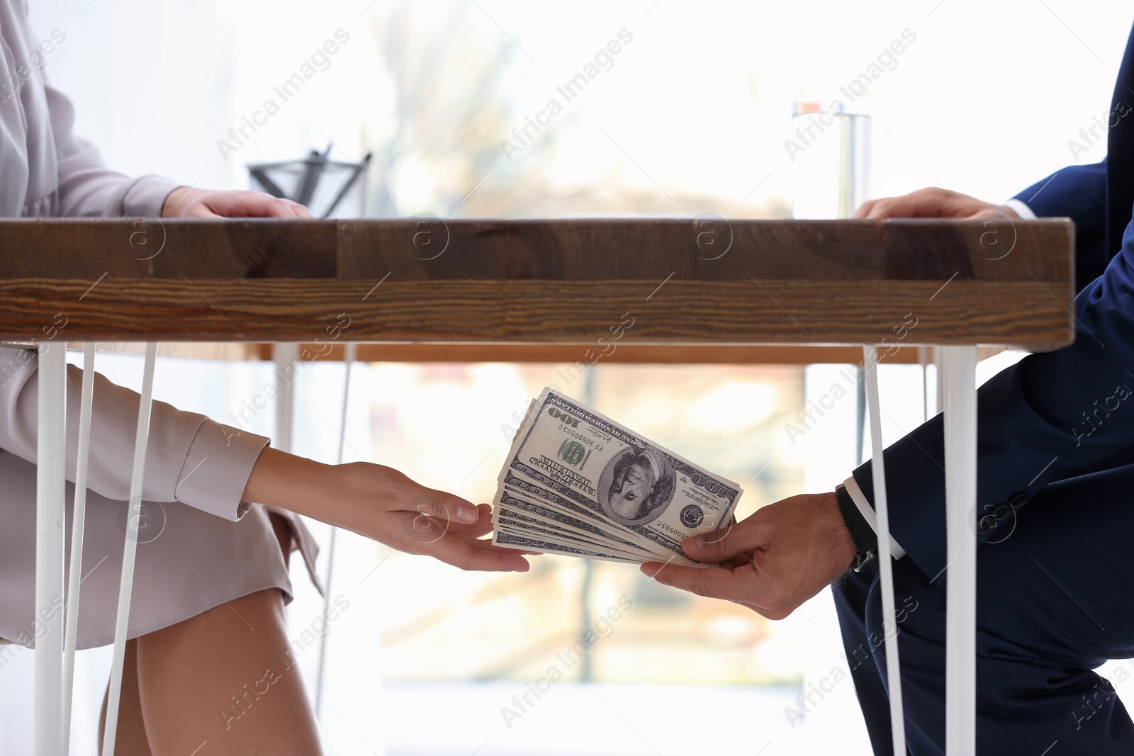 Photo of Man giving bribe money under table indoors, closeup