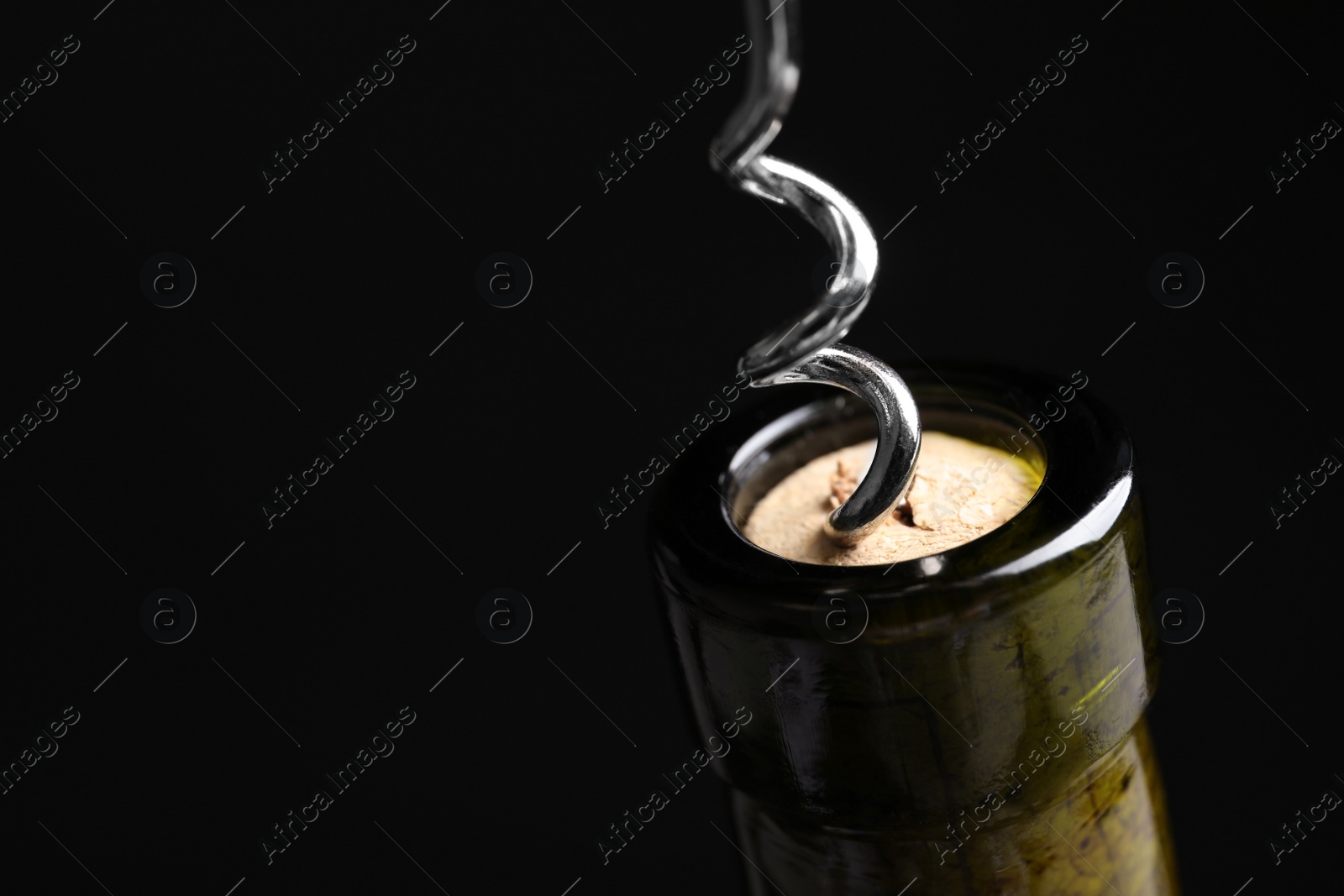Photo of Opening wine bottle with corkscrew on black background, closeup. Space for text
