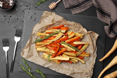 Photo of Tasty baked parsnip and bell pepper served on dark grey table, flat lay