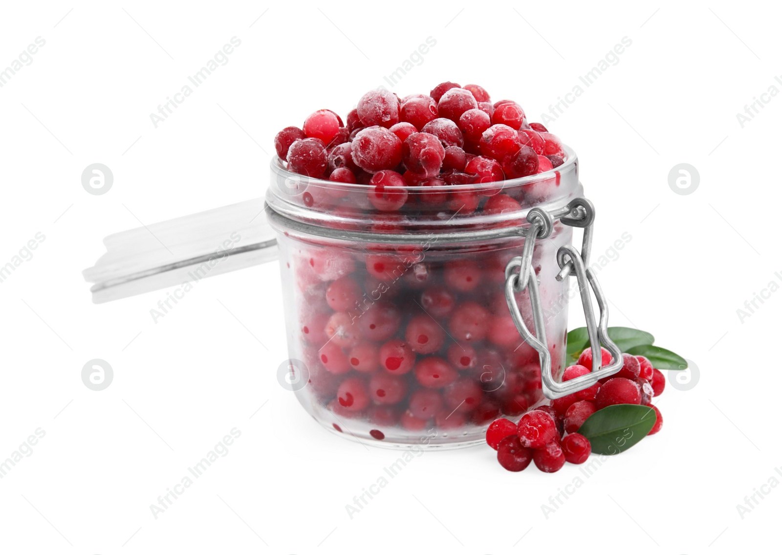 Photo of Frozen red cranberries in glass jar and green leaves isolated on white