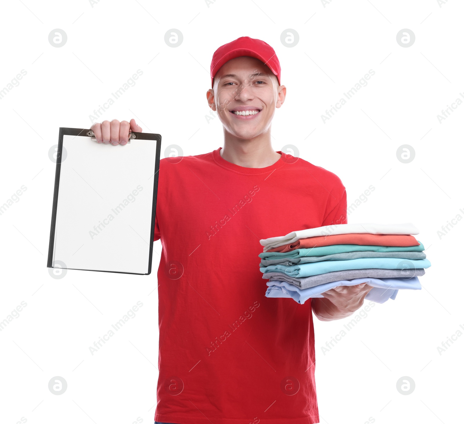 Photo of Dry-cleaning delivery. Happy courier holding folded clothes and clipboard on white background