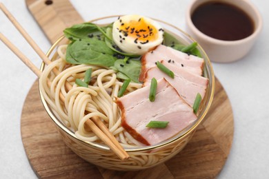 Photo of Delicious ramen with meat on white table, closeup. Noodle soup