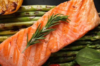 Photo of Tasty grilled salmon with asparagus and rosemary on plate, top view