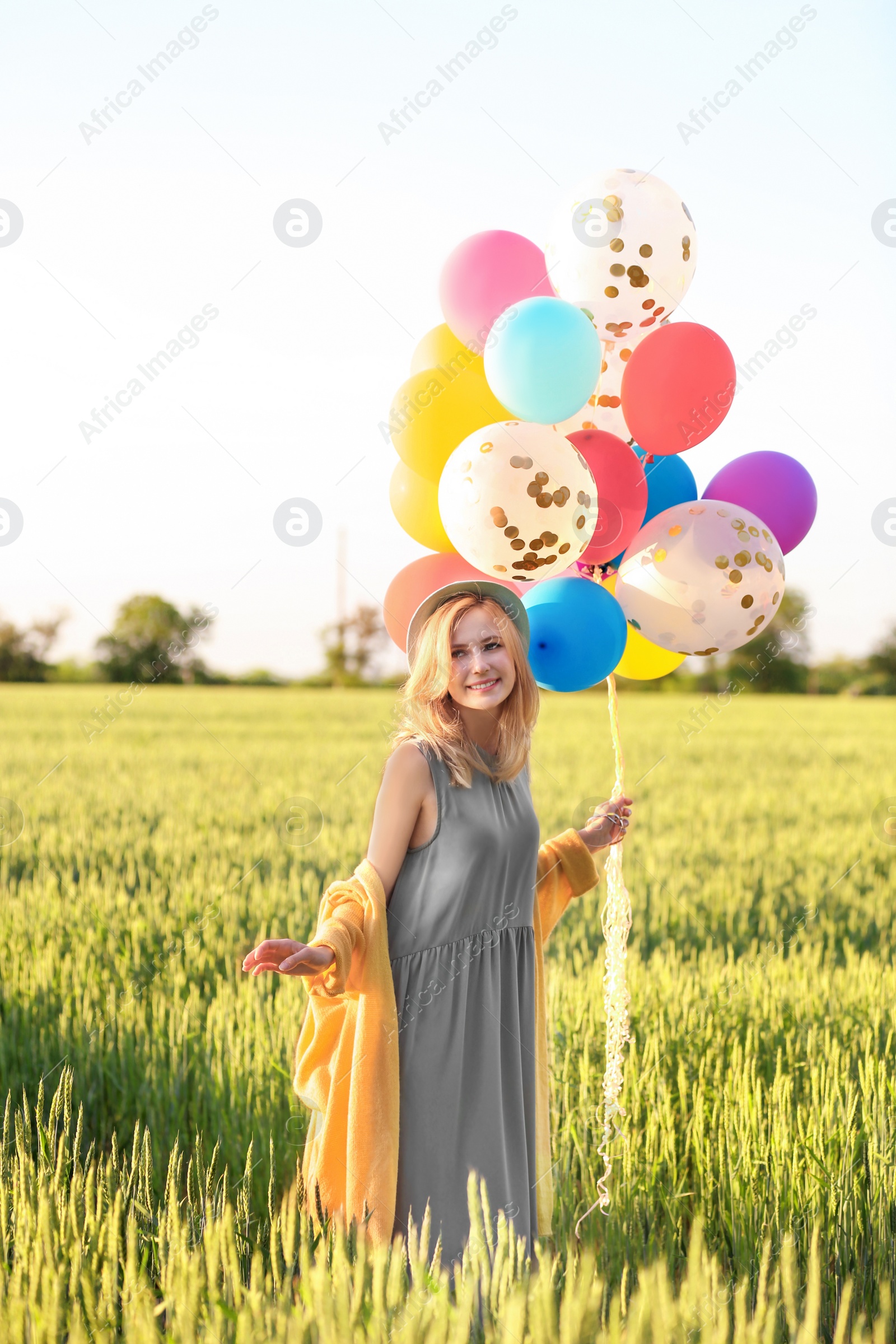 Photo of Young woman with colorful balloons in field on sunny day