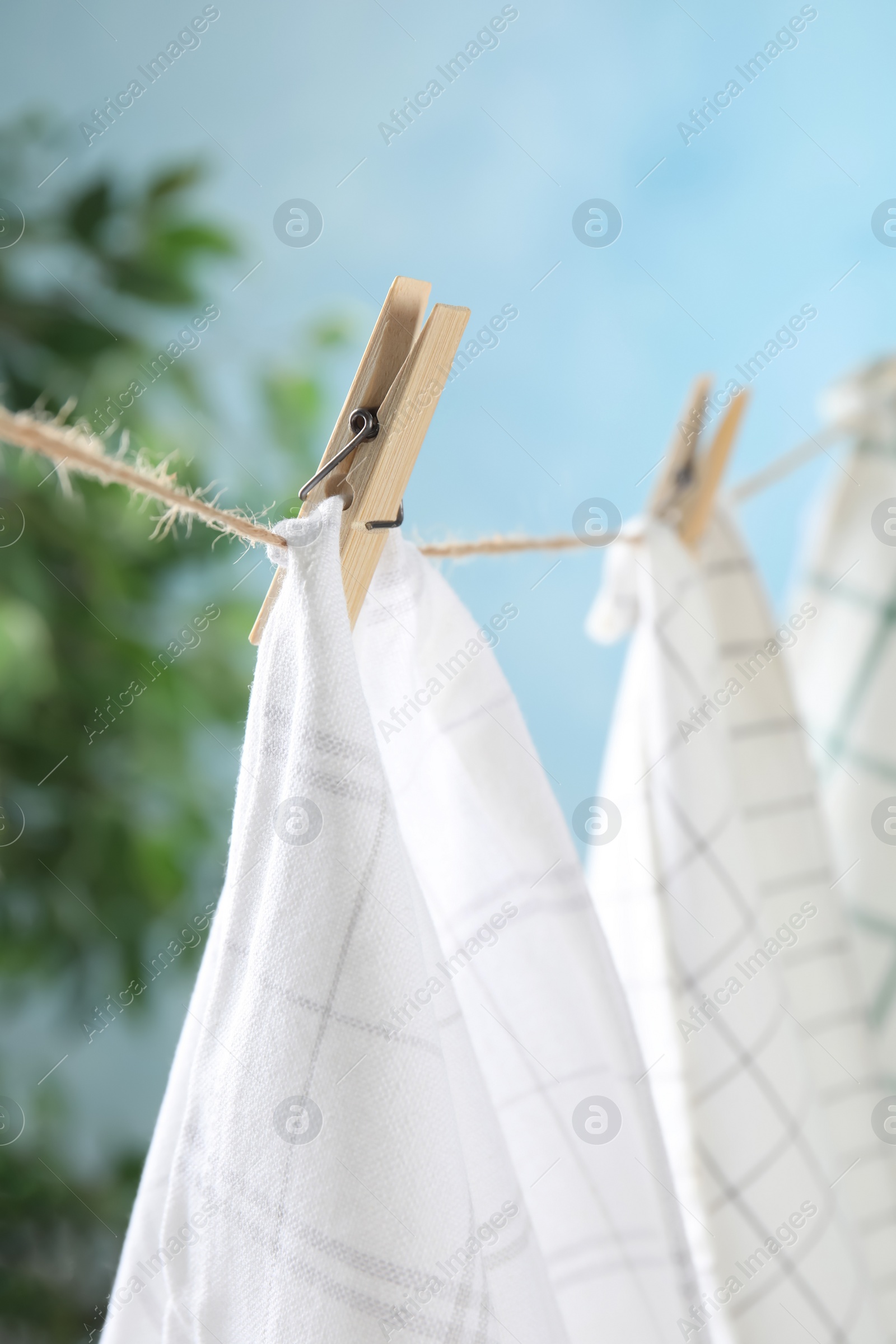 Photo of Washing line with wooden clothespins and fabrics against blurred background