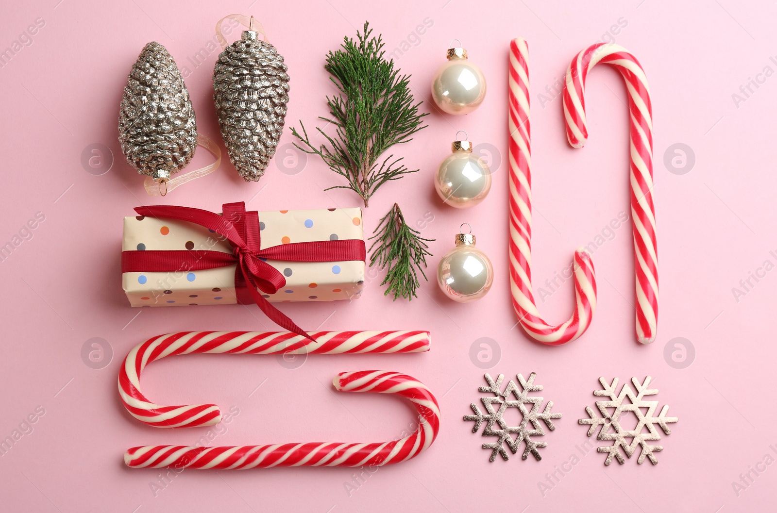 Photo of Flat lay composition with candy canes and Christmas decor on pink background