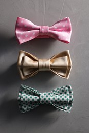 Stylish color bow ties on gray textured background, flat lay