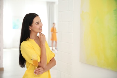 Photo of Young woman with glass of champagne at exhibition in art gallery