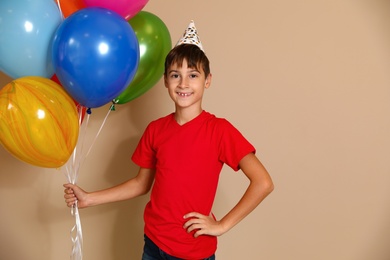 Happy boy with balloons on brown background. Birthday celebration