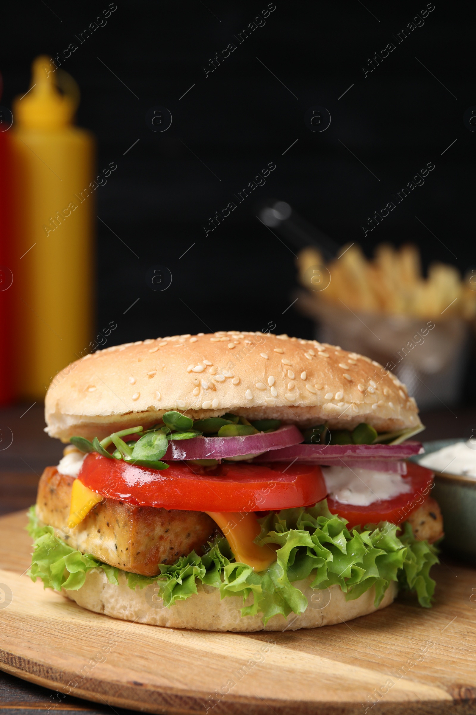 Photo of Delicious burger with tofu and fresh vegetables on wooden board