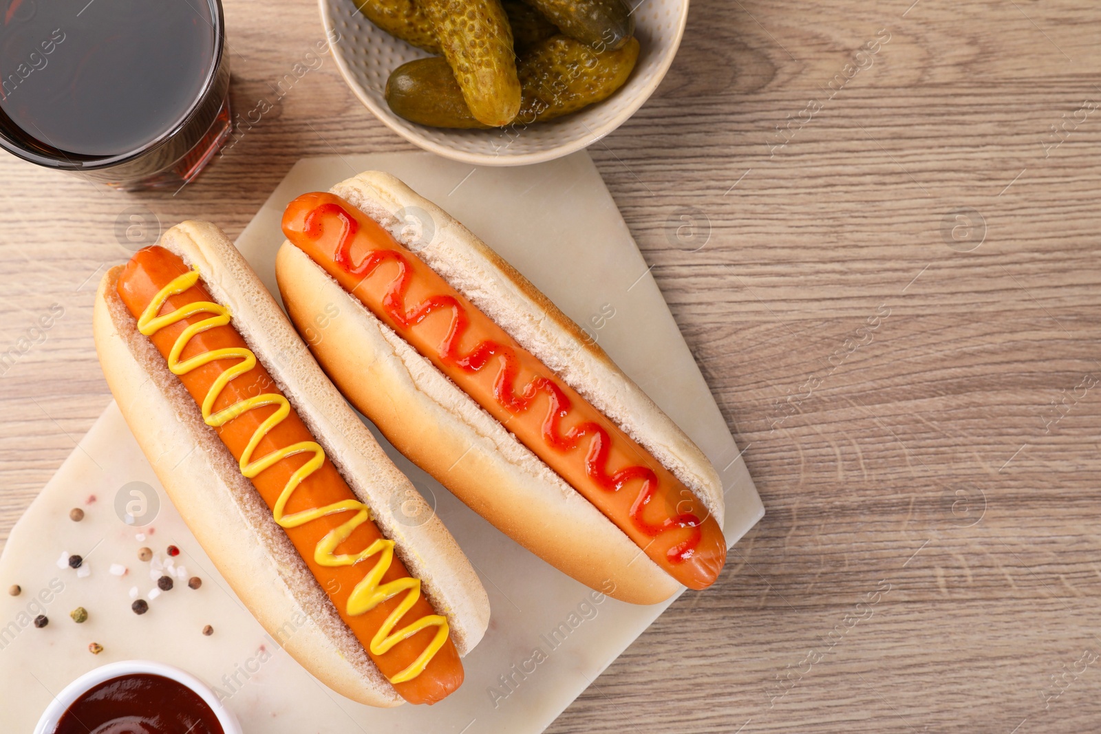 Photo of Tasty hot dogs with ketchup and mustard served on wooden table, flat lay