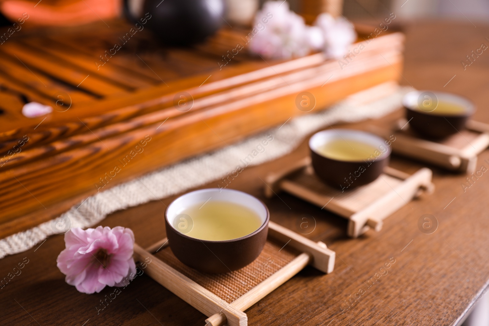 Photo of Cups with freshly brewed tea during traditional ceremony on wooden table