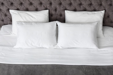 Soft white pillows on comfortable bed, closeup