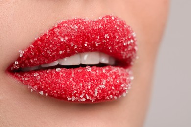 Photo of Young woman with beautiful lips covered in sugar, on light background, closeup