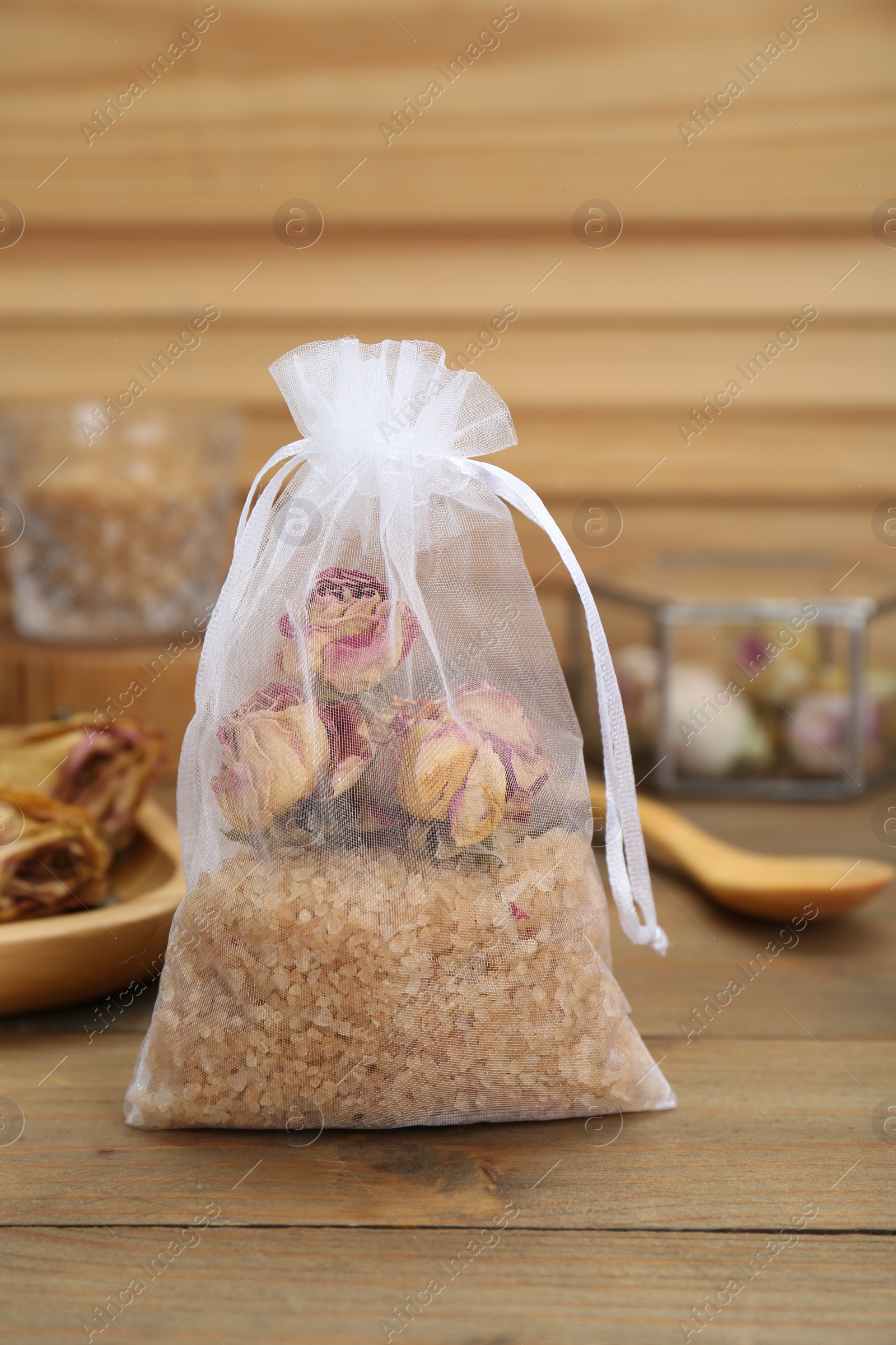 Photo of Scented sachet with dried roses and sea salt on wooden table