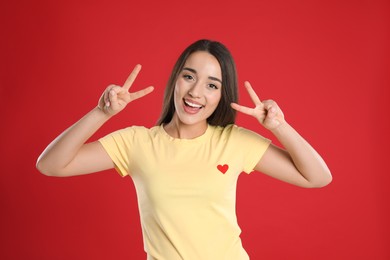 Woman in yellow t-shirt showing number four with her hands on red background