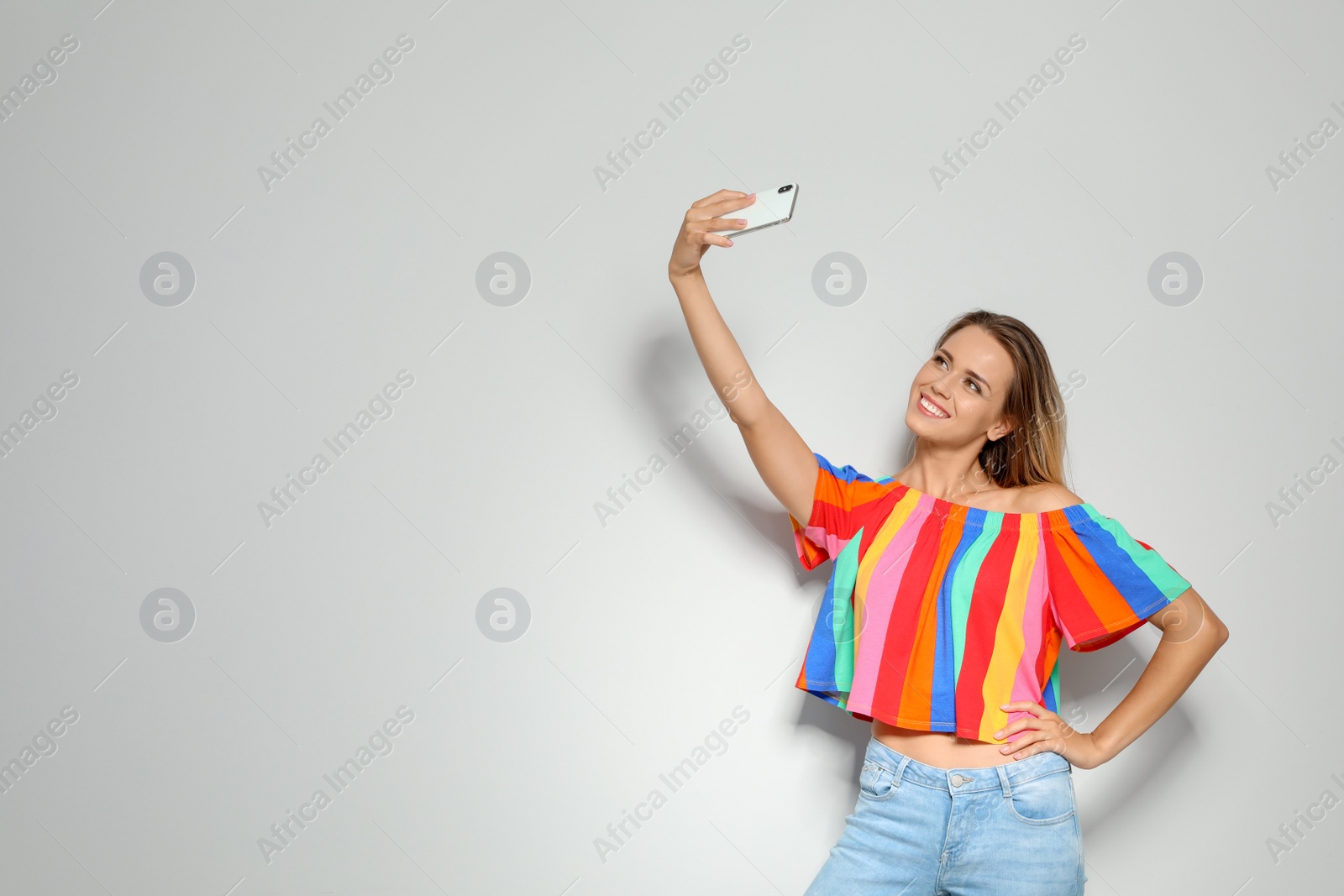 Photo of Beautiful woman taking selfie on light background