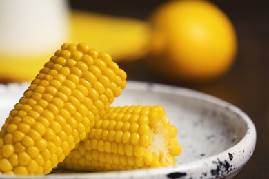 Photo of Plate with ripe corn cobs on blurred background, closeup