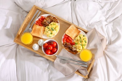 Photo of Good morning. Tray with tasty breakfast on bed, top view