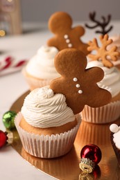 Photo of Tasty Christmas cupcake with gingerbread man and baubles on white table
