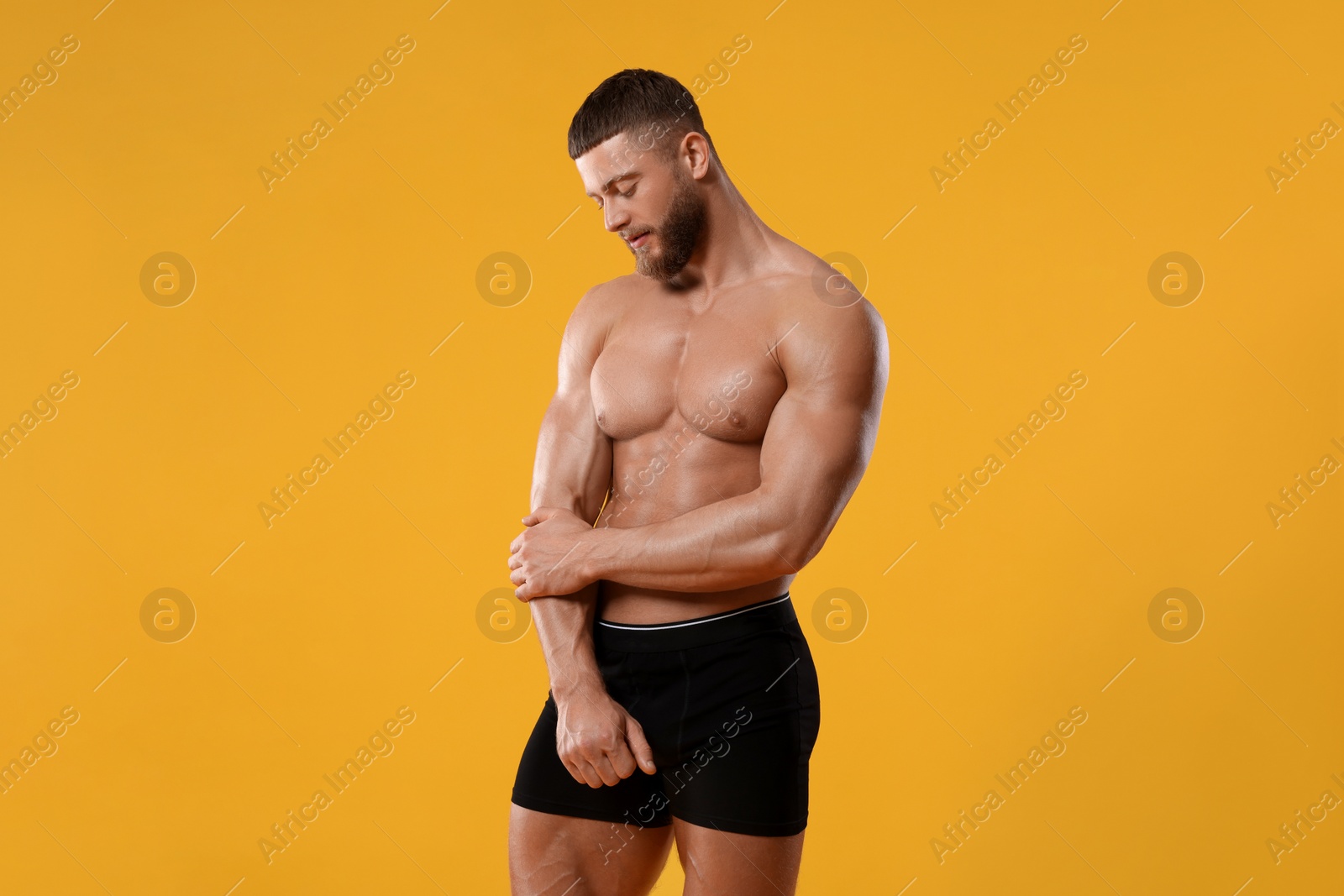 Photo of Young man is stylish black underwear on orange background